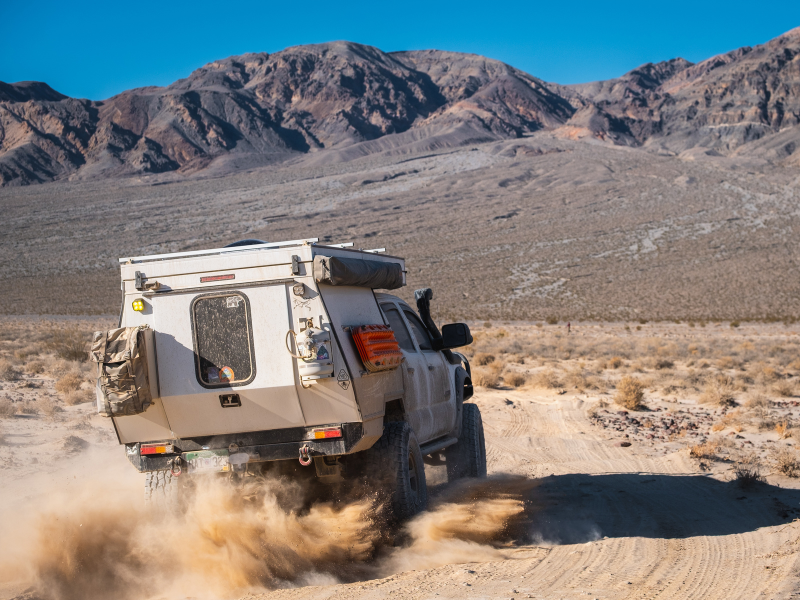 Off-road vehicle driving on a dirt road with mountains in the background